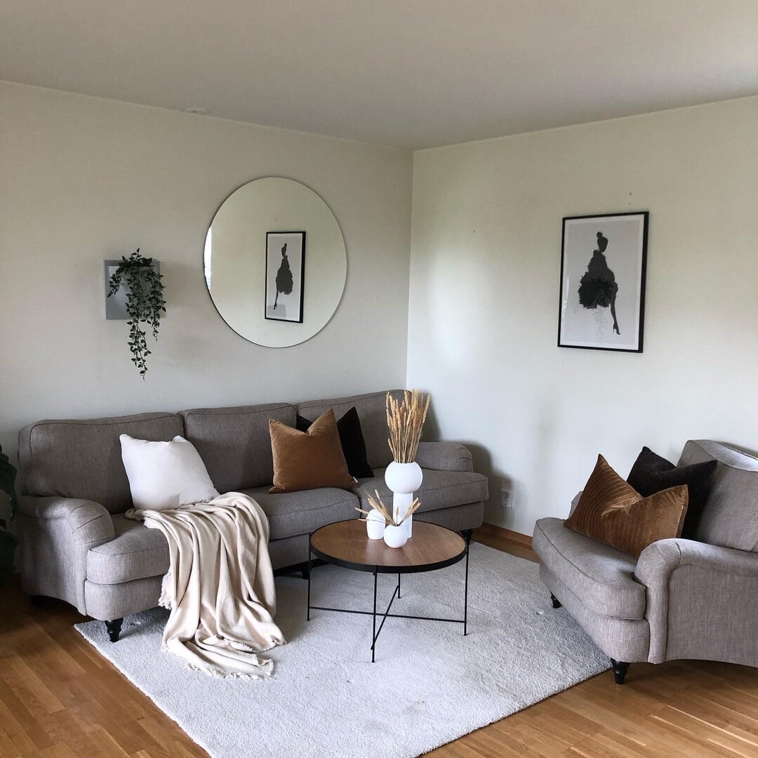 Elegant stue med moderne møbler, dekorative puter, veggkunst og planter, perfekt for hjemmet. Fokus på renhold og styling for et innbydende hjem.